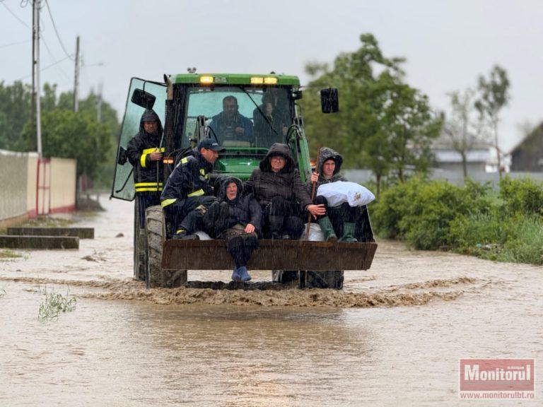 Oameni evacuaţi cu excavatorul din calea apelor (VIDEO)
